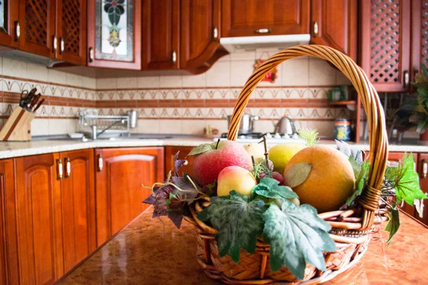 Interior de una cocina de madera. Cesta decorativa con frutas en la mesa — Foto de Stock