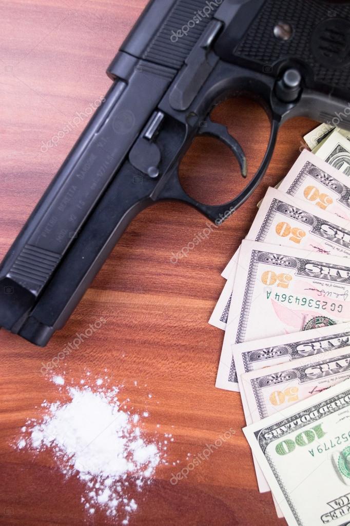 Gun, drugs and money on wooden background