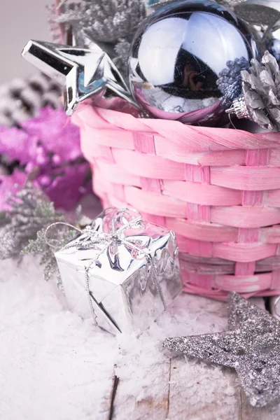 Рожевий різдвяний кошик зі срібними іграшками на білому дерев'яному фоні — стокове фото
