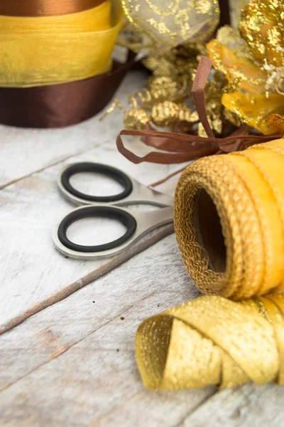 Carta da regalo dorata e fiocco per addobbi natalizi su legno — Foto Stock