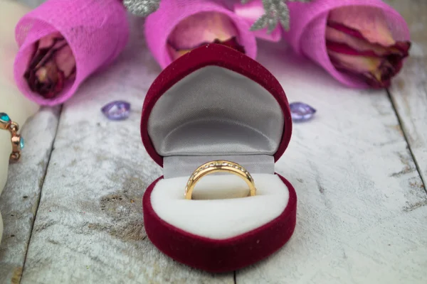 Wedding ring among roses on wood background — Stock Photo, Image