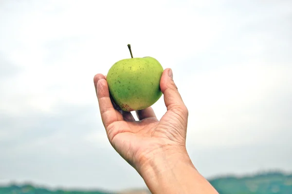 Una mela esposta verso il cielo con una mano — Fotografia de Stock