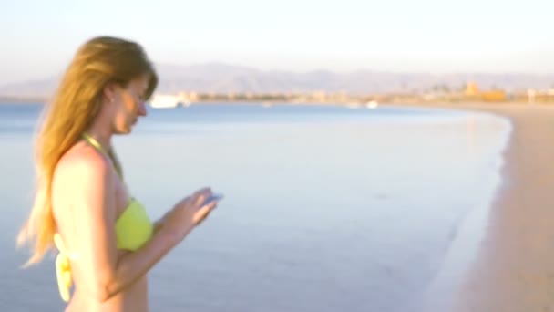 La fille au bord de la mer écrit un message au téléphone. HD — Video