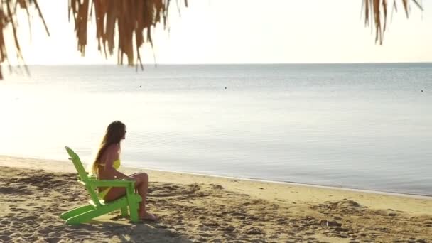 A menina toma banho de sol na praia com vista para o mar. HD — Vídeo de Stock