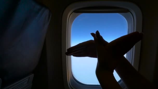 Las manos hacen el gesto de pájaros volando en el fondo de la ventana del avión. HD — Vídeo de stock