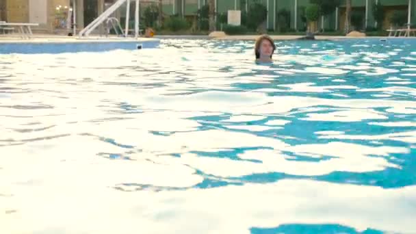 A menina nada em uma piscina sob o céu aberto. HD — Vídeo de Stock