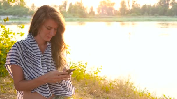 Una joven atractiva escribe un mensaje por teléfono. HD — Vídeos de Stock