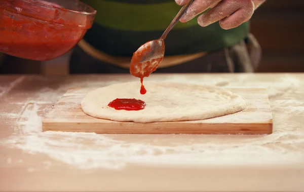Verter salsa de tomate en una pizza —  Fotos de Stock