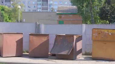 Şehir caddesinde kaldırımda duran metal çöp bidonları.