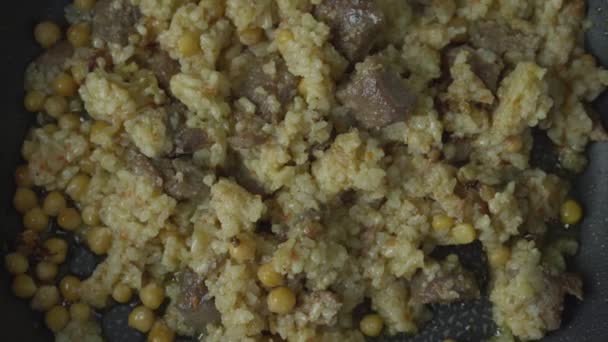 Pilaf con riso e carne di agnello o di manzo frittura su padella nera da vicino vista dall'alto — Video Stock