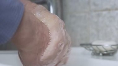 Emekli adam kırışık ellerini sabun jölesi ile yıkıyor. Coronavirüs konsepti.