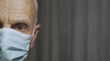 Yüzü maske takan, üzgün gözlü, sağlık hizmetleri konsepti olan yaşlı bir adamın yarısı.