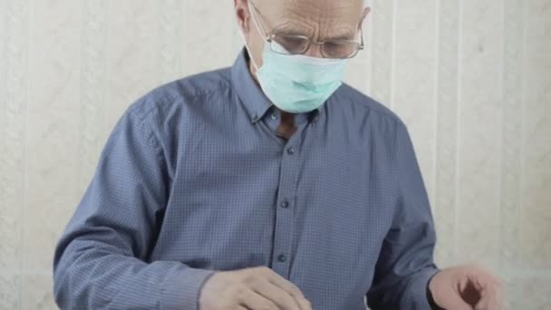 Elder man wearing face mask and glasses solving crossword puzzles — Stock Video