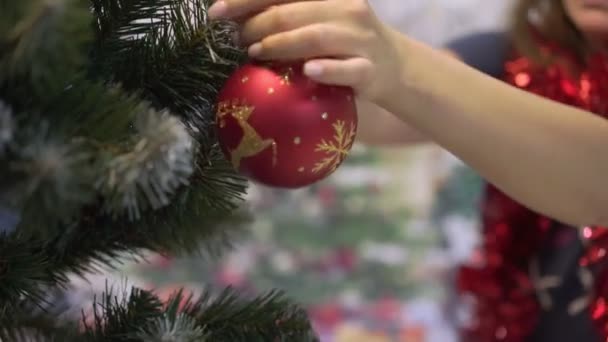 Mãos femininas pendurado brinquedo bola na árvore de Natal conceito de celebração do ano novo — Vídeo de Stock