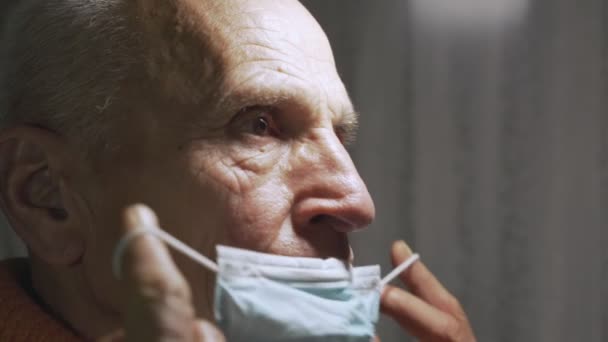 Sjuk man bär skyddande ansiktsmask och tittar åt sidan på sjukhus — Stockvideo