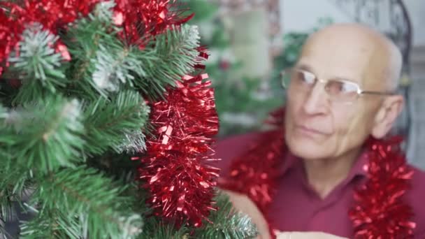 Idős férfi mosollyal az arcán lógó piros labdát karácsonyfa — Stock videók