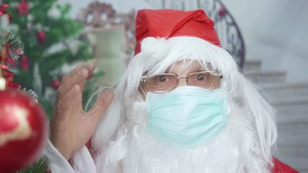 Санта-Клаус в красной кепке и медицинской маске поздравляет с Новым годом онлайн — стоковое видео
