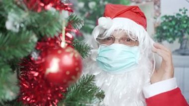 Noel ağacından maske ve gözlük takan komik yaşlı Noel Baba.