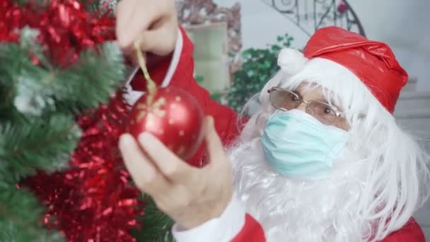 Παλιά Santa Claus σε μάσκα πρόσωπο μίας χρήσης διακοσμούν χριστουγεννιάτικο δέντρο με κόκκινη μπάλα — Αρχείο Βίντεο