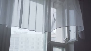 Sert rüzgâr açık pencere yaprağından esiyor ve dalgalar şeffaf ince perdeden geçiyor.