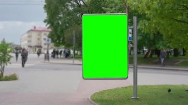 Metal direğin üzerindeki dikey reklam pankartı şehir yolunun yanındaki kaldırımda duruyor..