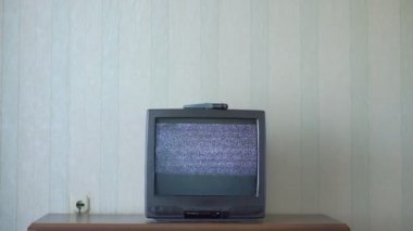 Parazit sesli video görüntüsü olan eski televizyon odaların ahşap masasında duruyor.