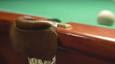 Oyuncu bilardo topunda ahşap ıstakayla tekme atıyor ve top cebine düşüyor.