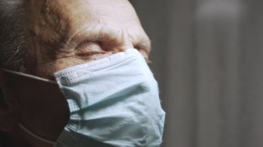 Yaşlı adamın yüzündeki korku ifadesi aşılar sırasında tıbbi maske takıyor..