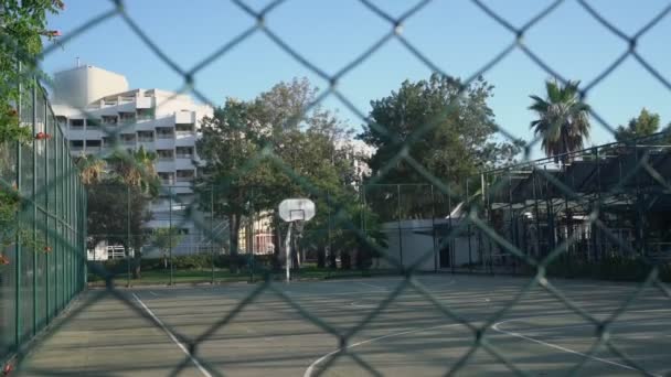 Empty closed basketball playground behind high metal fence. — Stock Video