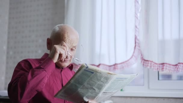 疲れた老人タッチ病気の目とともに手と読書新聞 — ストック動画