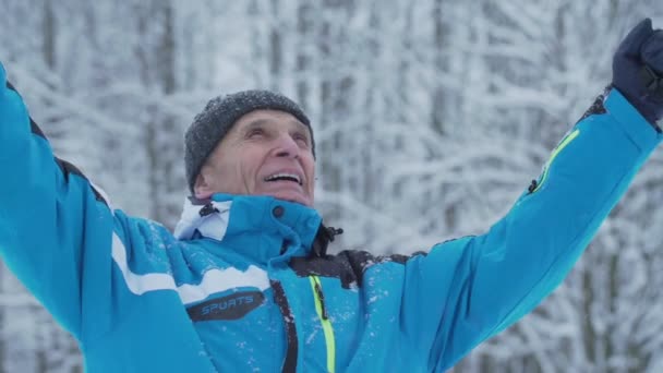 Starszy turysta podnosi ręce stojąc w górach w sezonie zimowym. — Wideo stockowe