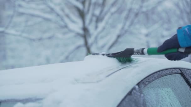 Main masculine avec brosse balayant la neige du toit de la voiture en hiver ou au printemps — Video