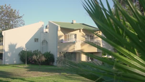 Resort bungalow gevel uitzicht door palmbomen bladeren in resort hotel grondgebied. — Stockvideo