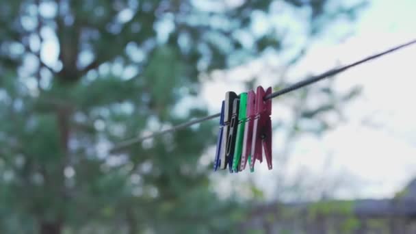 Veelkleurige kledingspelden hangen aan touw in de tuin van het dorp — Stockvideo