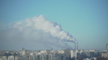 Fabrika bacalarından çıkan beyaz duman şehrin üzerinde mavi gökyüzünde dönüyor.