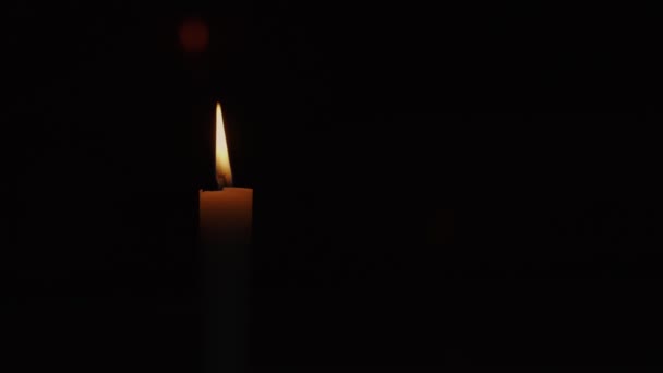 Plamen voskově žluté svíčky osvětluje tmavý prostor s jasným klidným světlem. — Stock video