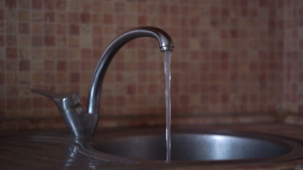 Wasser strömt im vertikalen Strom aus dem Wasserhahn in die Spüle in der Küche — Stockvideo