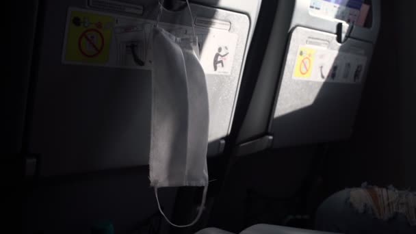 Beyaz tıbbi maske uçuş sırasında uçak koltuğunda asılı durur. — Stok video
