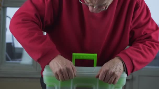 Senior man wearing glasses opens plastic toolbox and takes solderer. — Stock Video