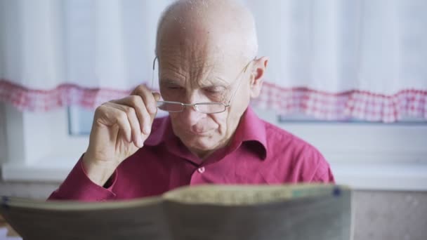 Homme chauve senior garde les lunettes dans la main corrige et lit le journal. — Video