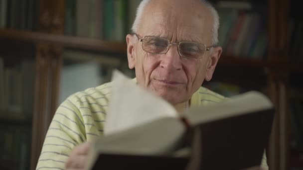 Serious intellectual senior man in eyeglasses reads big book. — Stock Video