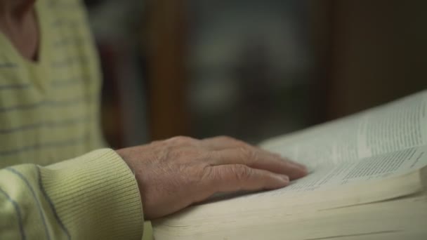 Gerimpelde hand van senior man blad door pagina 's van oude grote Bijbel boek. — Stockvideo