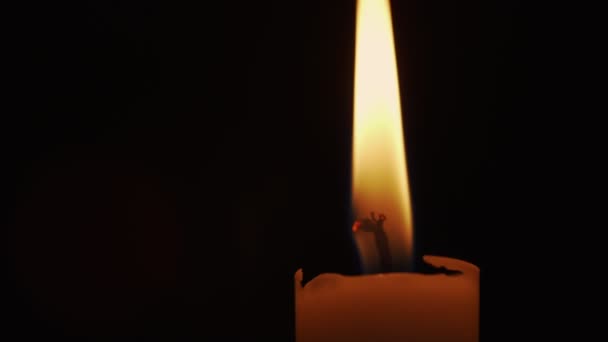 Висока жовта свічка, що горить на свічці, рухається в темній кімнаті — стокове відео