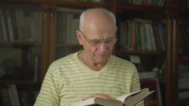 Старий залишає сторінки книг, що стоять проти книжкової шафи — стокове відео