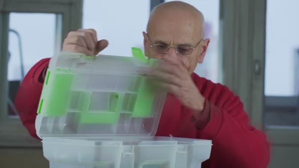 Menuisier senior dans les lunettes ouvre boîte à outils et prend de tournevis et clé — Video