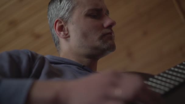 Caucasien homme apprend à jouer de la guitare en ligne à la recherche d'un ordinateur portable — Video