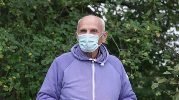 Oudere kale boer draagt gezichtsmasker houdt rode appels in de hand — Stockvideo