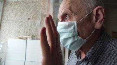 Yüz maskeli yaşlı adam arkadaşlarıyla buluşmayı ve el sallamayı bekler..