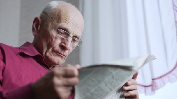 Grave uomo anziano in occhiali leggere giornale sotto la luce elettrica. — Video Stock