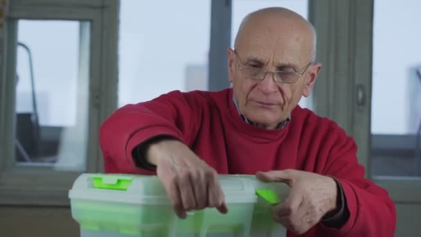 Carpinteiro sênior usando óculos leva de ferramenta da caixa de ferramentas — Vídeo de Stock